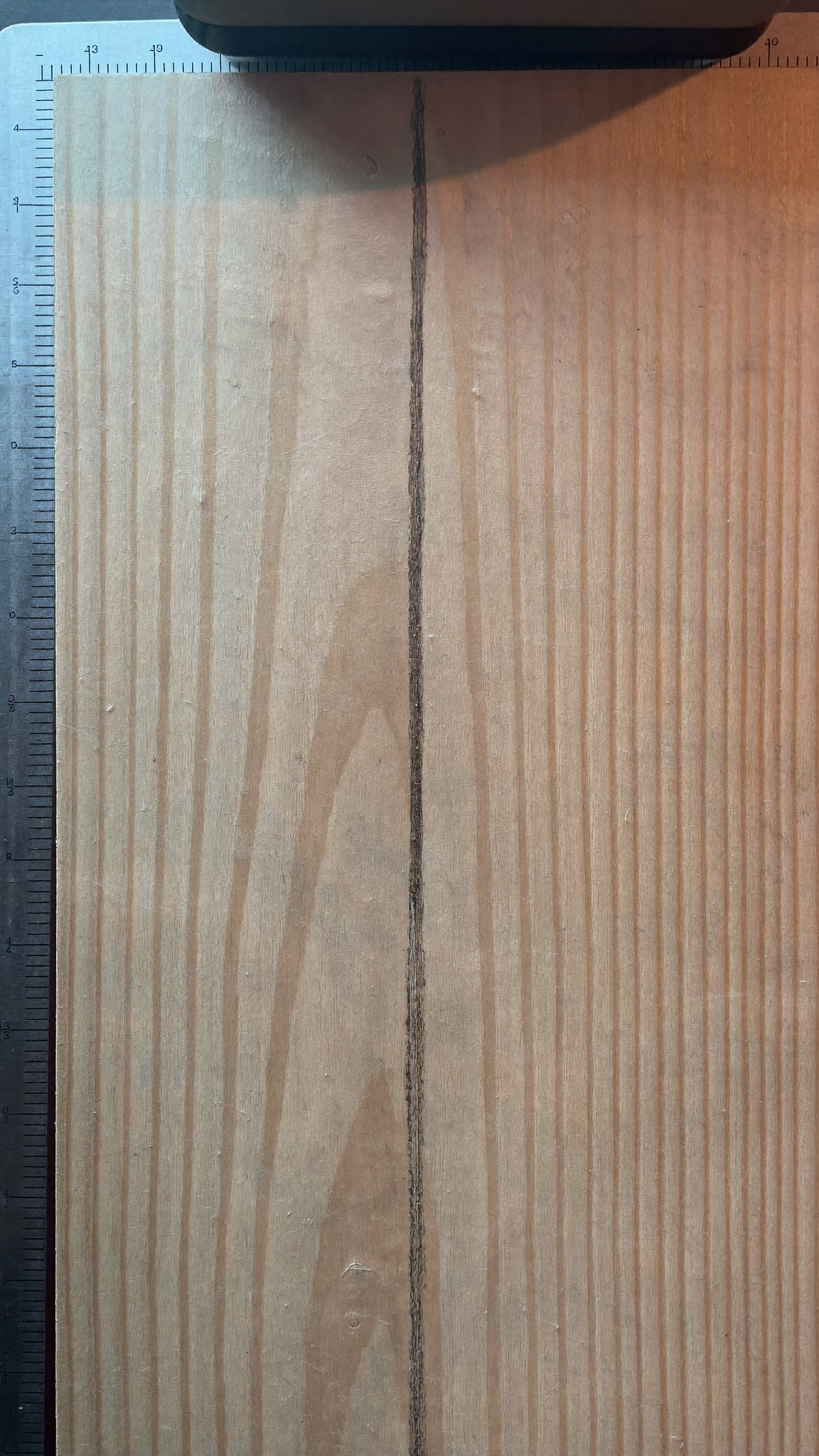 Pencil line marked on a wood board beside a metal rule